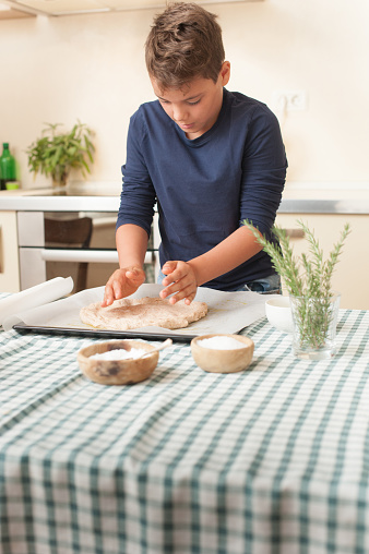 Boy Stretching Focaccia Dough Into Baking Pan