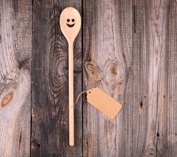 istock wooden spoon with embedded eyes and a smile, empty brown paper tag 1146085832