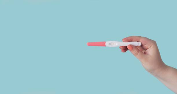 istock Unrecognizable woman holding a pregnancy test. Panoramic image with copy space. 1146088302