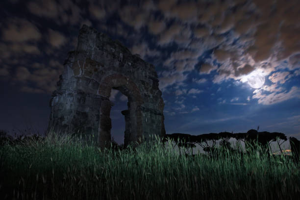 Ruins of an ancient Roman aqueduct in a night scene, with the full moon.