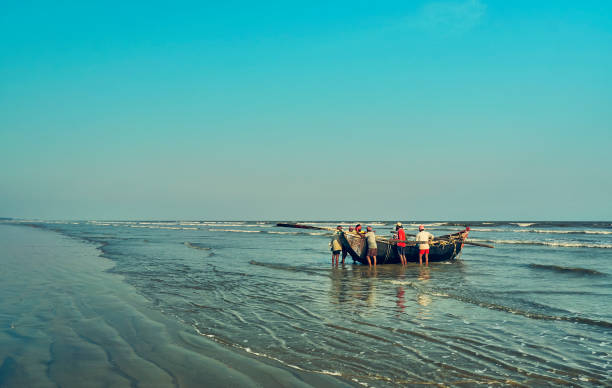 Fisherman returning home at day's end .. with their boat, sea beach at Shankarpur, West Bengal A group of fishermen returning home at day's end, after fishing in deep sea for the whole day. They will go to their village, where the fish will be distributed among them.

Photo taken at Shankarpur, a traditional fishing village near Digha, a popular tourist destination. Photo taken on 04/20/2019 in evening. bay of bengal stock pictures, royalty-free photos & images