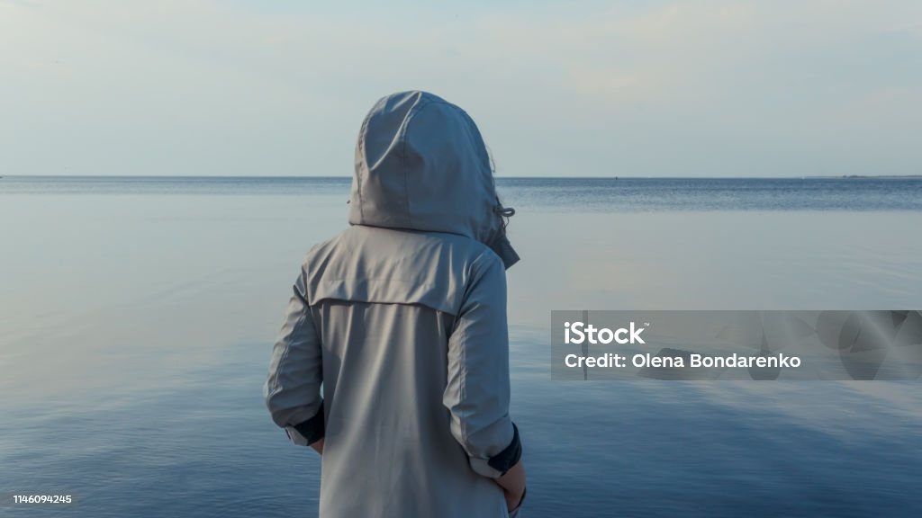 De pennen vrouw staande in de buurt van de zee. Het meisje kijkt naar de horizon - Royalty-free Volwassen vrouwen Stockfoto