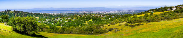 View towards Redwood City and Menlo Park; hills and valleys covered in green grass and wildflowers visible in the foreground, Silicon Valley, San Francisco bay, California View towards Redwood City and Menlo Park; hills and valleys covered in green grass and wildflowers visible in the foreground, Silicon Valley, San Francisco bay, California san francisco county city california urban scene stock pictures, royalty-free photos & images