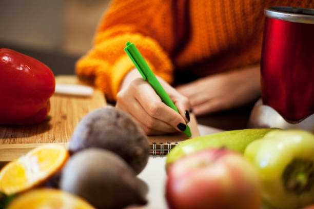 Housewife writing list to supermarket . Close up of woman writing in kitchen. shopping list stock pictures, royalty-free photos & images