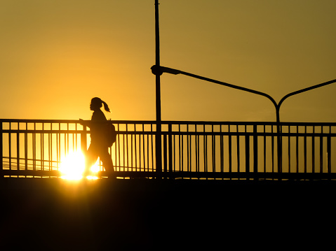 BANGKOK, APRIL 29: Silhouette of unknown city people walking across the overpass (Flyover) with sunset as a backdrop. Bangkok, Thailand.