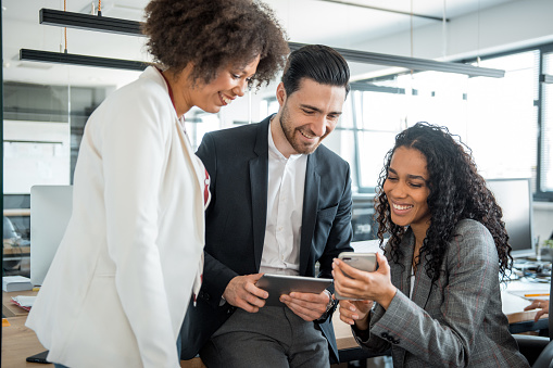 Small group of businesspeople using smart phones in the office and talking