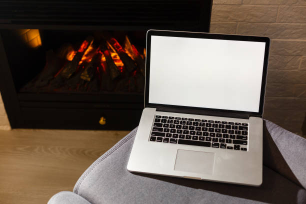 istock Mock up image of business man using and typing on laptop with blank white screen , sitting at indoor with fireplace background. Copy Space for text area 1146105622