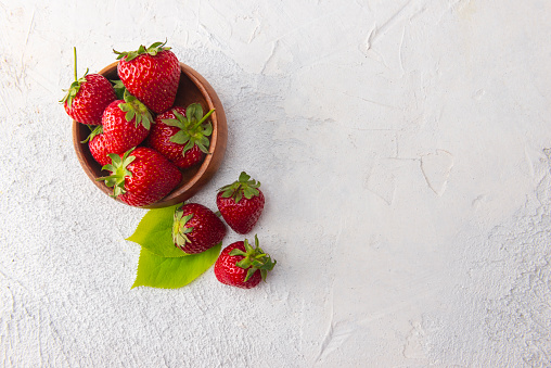 Many different fresh ripe berries and green leaves on dark grey table, flat lay