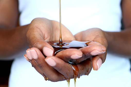 Black African hands cupped catching and holding pouring honey shot for beauty industry