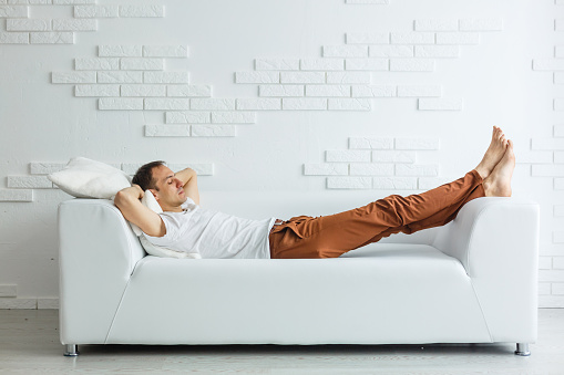 Calm handsome businessman sleeping on couch after work at home