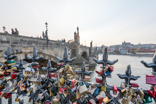 PRAGUE, CZECHIA - 10TH APRIL 2019: A huge selection of different colour and shapes of padlocks attached to metal railings along the Charles Bridge on the Vltava river in Prague - Early sunset, Spring, 2019