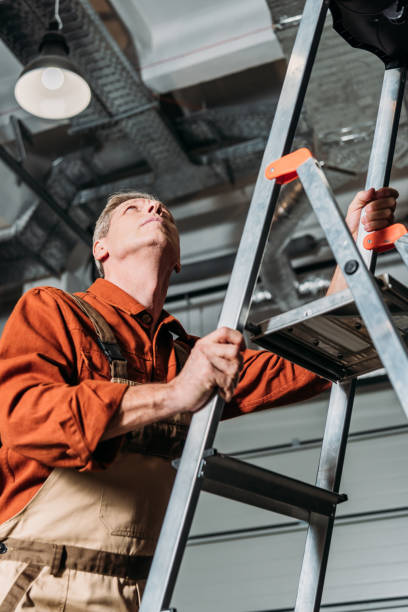 istock repairman in orange uniform standing on ladder in garage 1146110882
