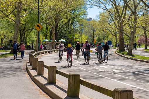 New York, United States - April 24, 2019: A group of people enjoying the sunny day, riding their bikes throught the central park