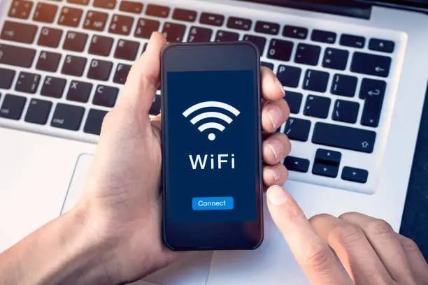 Photo of Connect to WiFi wireless internet network with smartphone at coffee shop or hotel with button on mobile device screen, free public hotspot secure access to web for email and website browsing