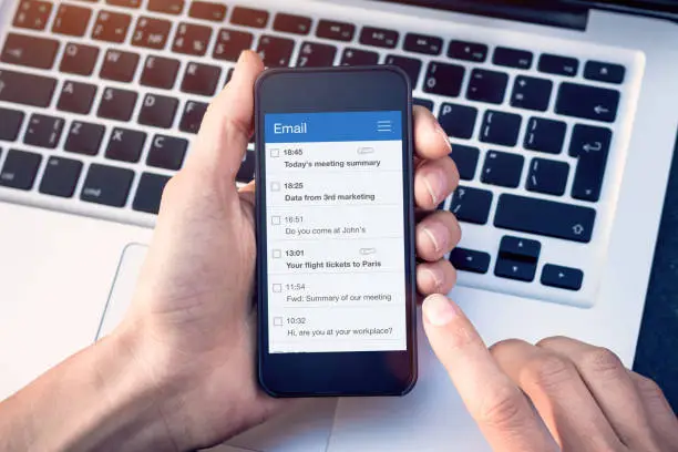 Photo of Email app on smartphone screen with business person reading messages from inbox with wireless internet access on mobile phone, communication technology