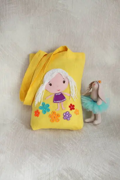 Photo of Yellow linen tote bag for a girl. Handmade summer bag with applique flowers. Fashion accessory for girls. Eco material. Decorative items on the tote bag for children.