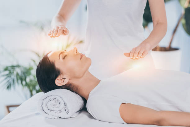 side view of calm young woman receiving reiki healing therapy on head and chest side view of calm young woman receiving reiki healing therapy on head and chest reiki photos stock pictures, royalty-free photos & images