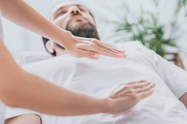 close-up view of bearded man receiving reiki healing session above stomach and chest stock photo