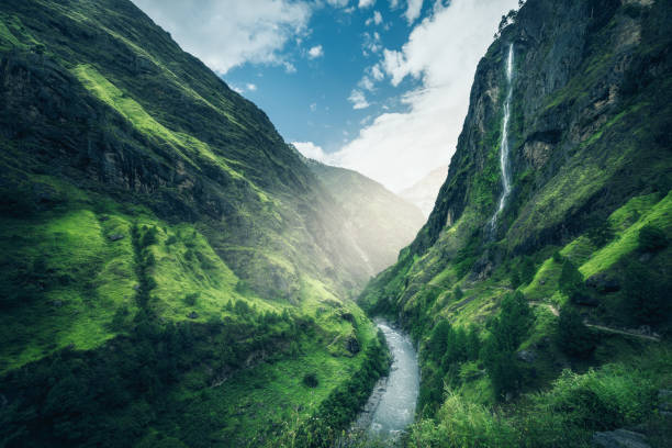 Beautiful mountains covered green grass. Moody landscape with mountain valley, river, waterfall, meadows and forest, sky with clouds in summer in Nepal in overcast day. Travel in Himalayas. Nature