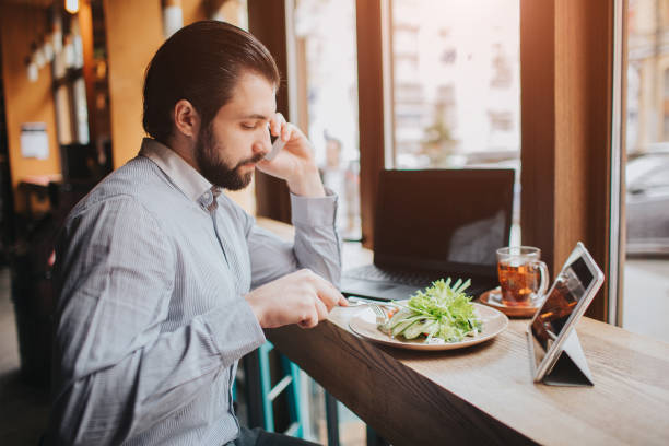 istock Busy man is in a hurry, he does not have time, he is going to eating and working. Worker eating, drinking coffee, talking on the phone, at the same time. Businessman doing multiple tasks. Multitasking business person. 1146126183