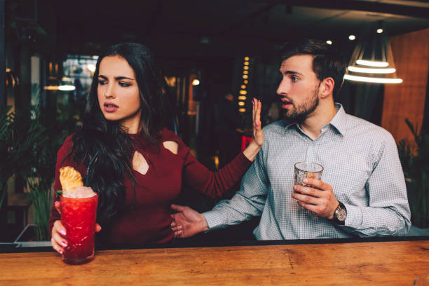 pessoas bonitas sentadas muito próximas umas das outras no stand do barman. ele quer falar com a garota enquanto ela se recusa a ouvi-lo. ela parece triste e zangada. - drinking couple bar counter bar - fotografias e filmes do acervo