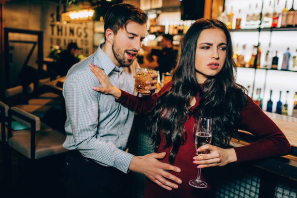 Very drunk man want to meet with beautiful girl. She refuses to meet with a guy who drank too much alcohol. She doesn;t like him at all. stock photo