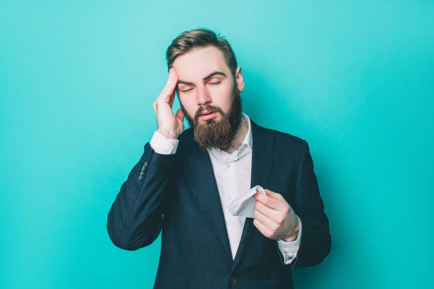 istock Man is holding his hand on the head. He has a headache. Guy is suffering from it. Also he has a napkin in the right hand. Isolated on blue background. 1146126339