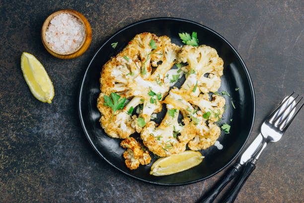 istock Fried cauliflower steak with greens and spices on dark background. 1146135300
