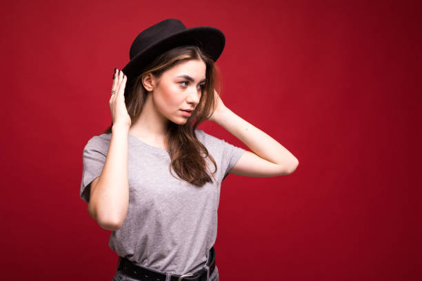 istock Young pretty woman with black hat standing isolated on red background 1146141372