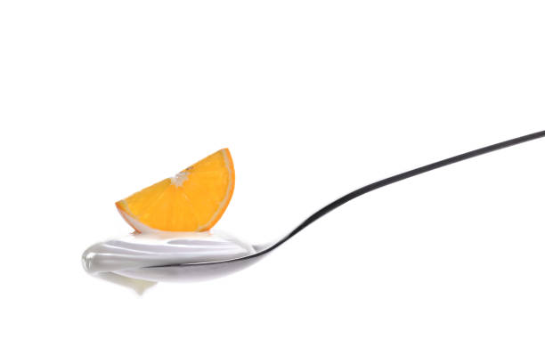 Plain yogurt on a spoon with fresh fruits on top isolated on white background