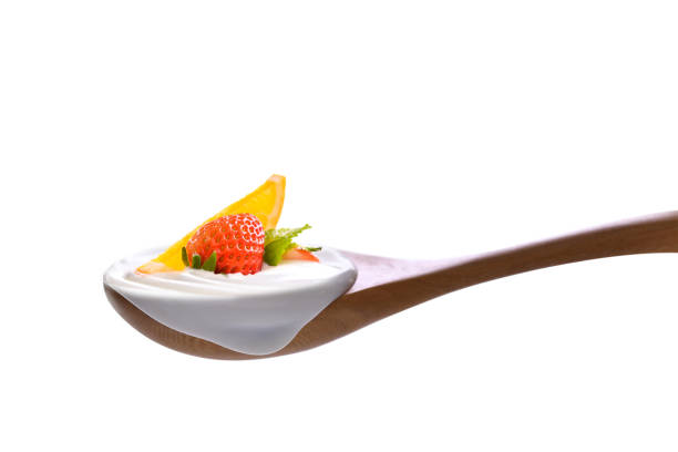 Plain yogurt on a spoon with fresh fruits on top isolated on white backgroud