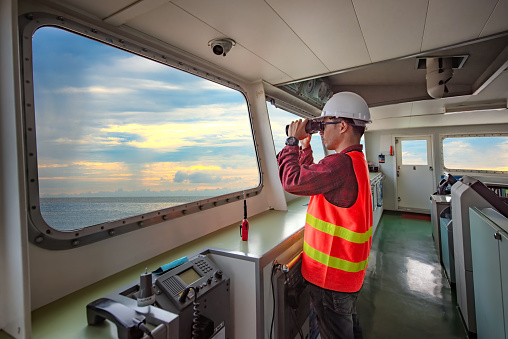 duty officer in charge handle of the ship navigating to the port destination, keep watching navigation on the bridge of the ship vessel under voyage sailing to the sea