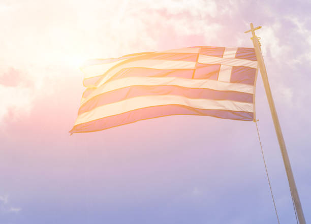 istock greek flag sun beams waving  on blue sky clouds greece 1146163408