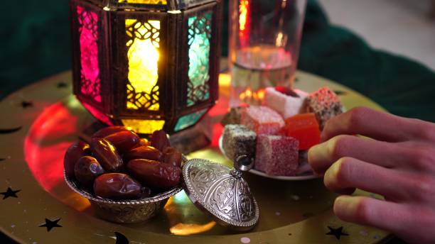 Evening meal during the Holy Muslim month of Ramadan. Dates, water, sweets and dried fruits A young man prays and drinks water and eats dates. Evening meal during the Holy Muslim month of Ramadan salah islamic prayer photos stock pictures, royalty-free photos & images