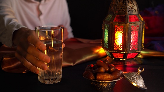 Un hombre joven reza y bebe agua y come citas. Cena durante el mes sagrado musulmán de Ramadán photo