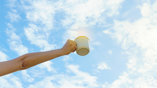 Asian woman hands hold hot coffee mug outdoor on clear sky background with copy space. Enjoy drinking coffee in the morning.