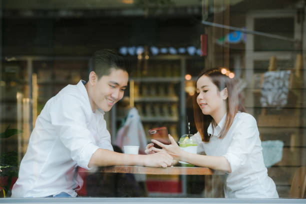 istock Asian couples checking phone together while sitting in cafe having coffee.Valentine day 1146190492