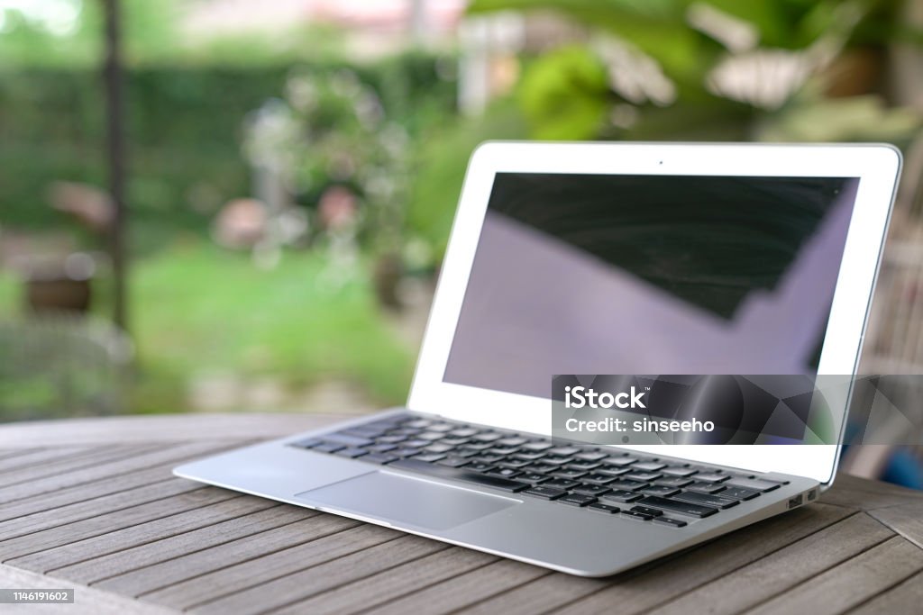 Laptop on wooden table Laptop, garden background. Outdoor or home office Laptop Stock Photo