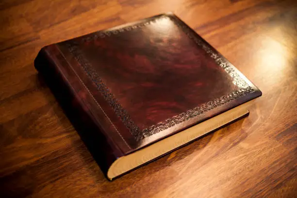 large leather-bound book on wooden background
