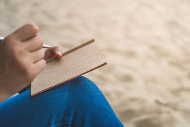 istock Woman hand writing down in small white memo notebook for take a note not to forget or to do list plan for future. 1146198527