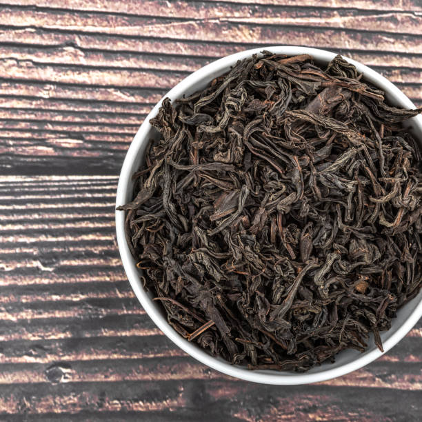 istock Dried tea is poured into a ceramic cup on a wooden plank table. View from above. 1146198716