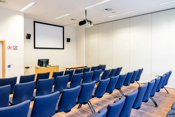 empty presentation room with rows of seats, projection screen and video projector on the ceiling. - event convention center business hotel imagens e fotografias de stock