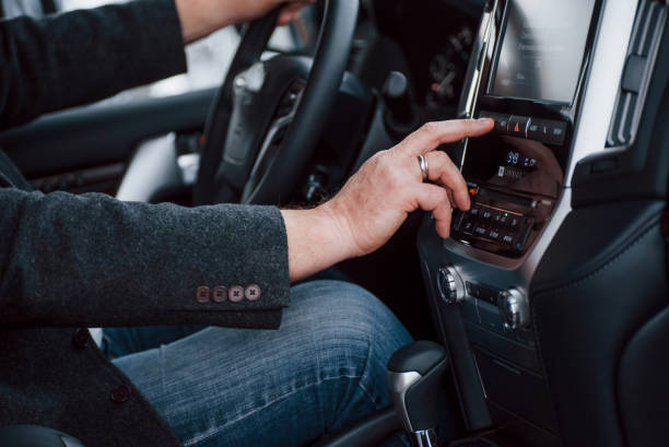 Turning off special functions. Businessman tests his new modern car. Black luxury interior of nice vehicle