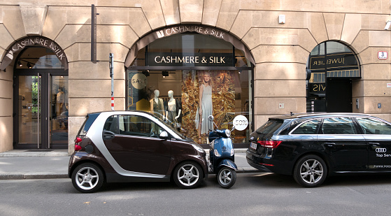 Vienna, Austria - July 20 2018: Two cars and a motorcycle are parked at the shop window of cashmere and silk in Vienna, Austria.