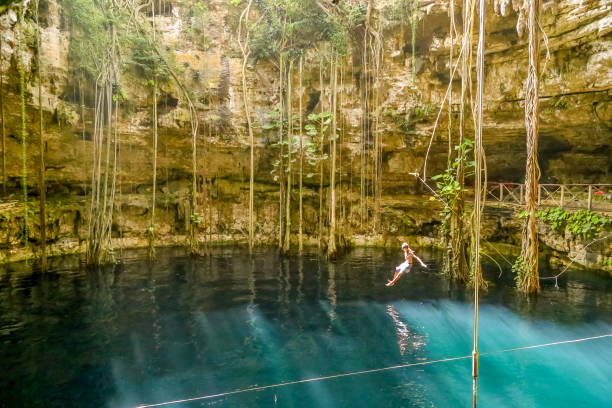 A young man jumping in a cenote at San Lorenzo Oxman. Valladolid Cenotes. Yucatan Peninsula, Mexico Yucatan, Mexico - October 30, 2014: A young man jumping in a cenote at San Lorenzo Oxman. Valladolid Cenotes. Yucatan Peninsula, Mexico, America valladolid mexico photos stock pictures, royalty-free photos & images