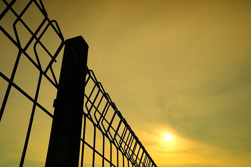 Silhouette of Steel Fence with Sunset Background.