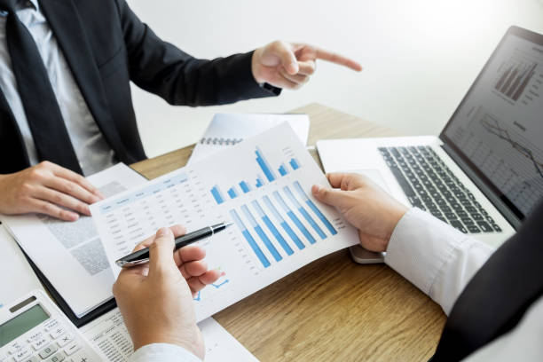 istock Midsection Of Coworkers Discussing Bar Graphs On Desk In Office 1146209411