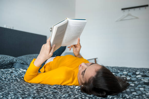 istock Young brunette woman reading a book and lying down on the bed 1146209905