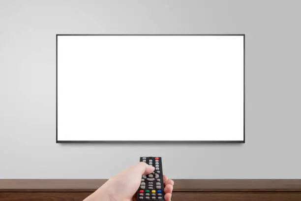 Photo of Television on white wall with hand using remote control, TV 4K flat screen lcd or oled, plasma realistic illustration, White blank HD monitor mockup.