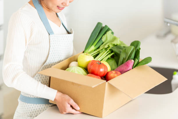Housewife with cardboard box containing various vegetables